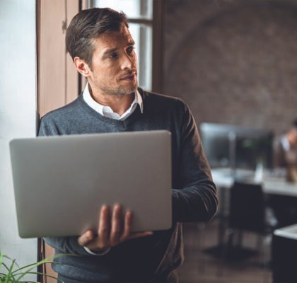 mid-adult-entrepreneur-thinking-something-while-using-computer-by-window-office-001