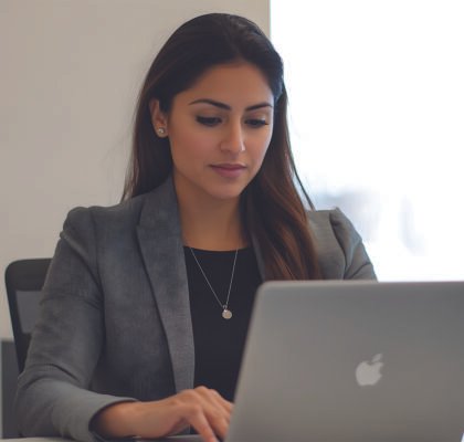woman-sits-front-laptop-with-silver-apple-logo-back-001